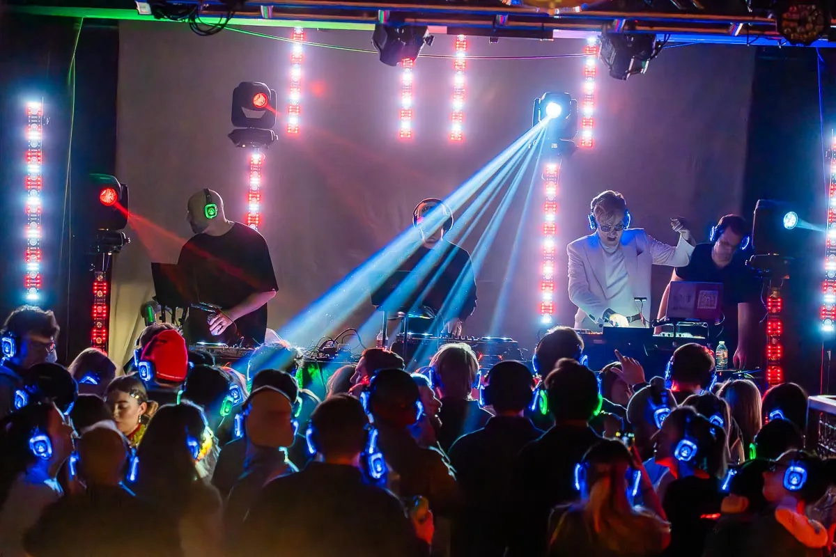 Guests wearing glowing headphones at a silent disco after-party with light beams