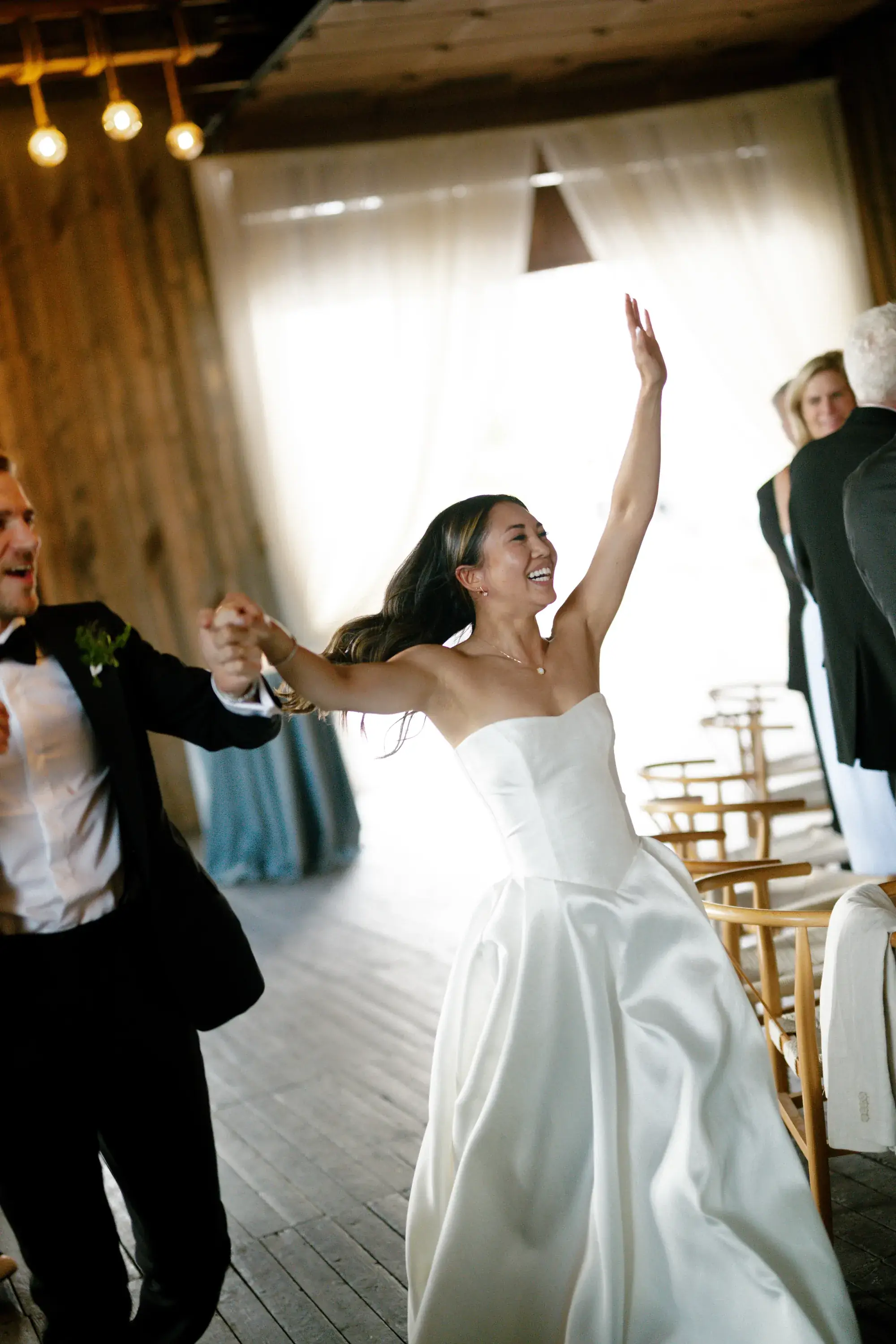 Bride and groom dancing beneath ivory drapes and string lighting at their Idaho wedding reception