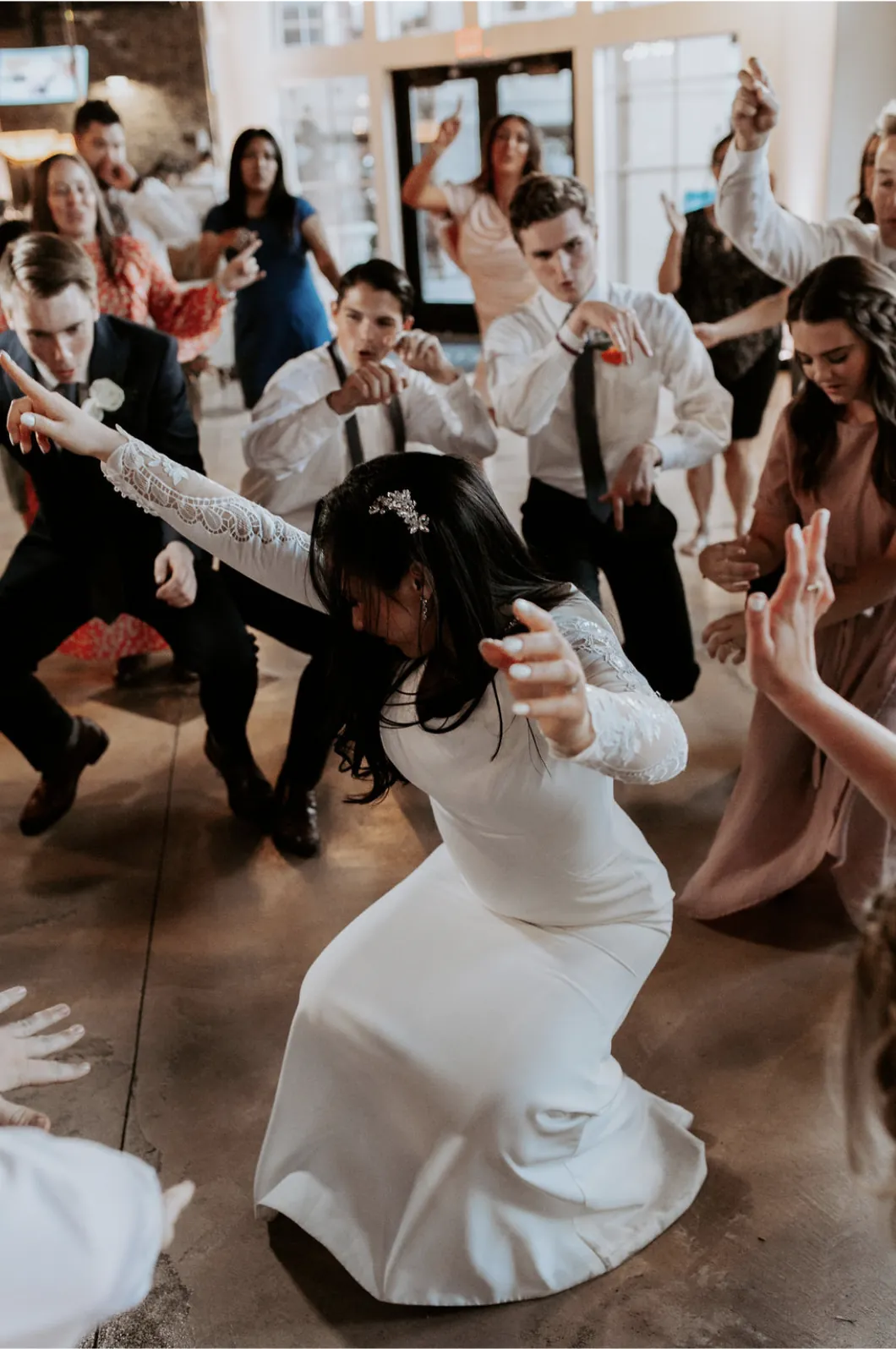Bride dancing low surrounded by cheering guests on a packed dance floor