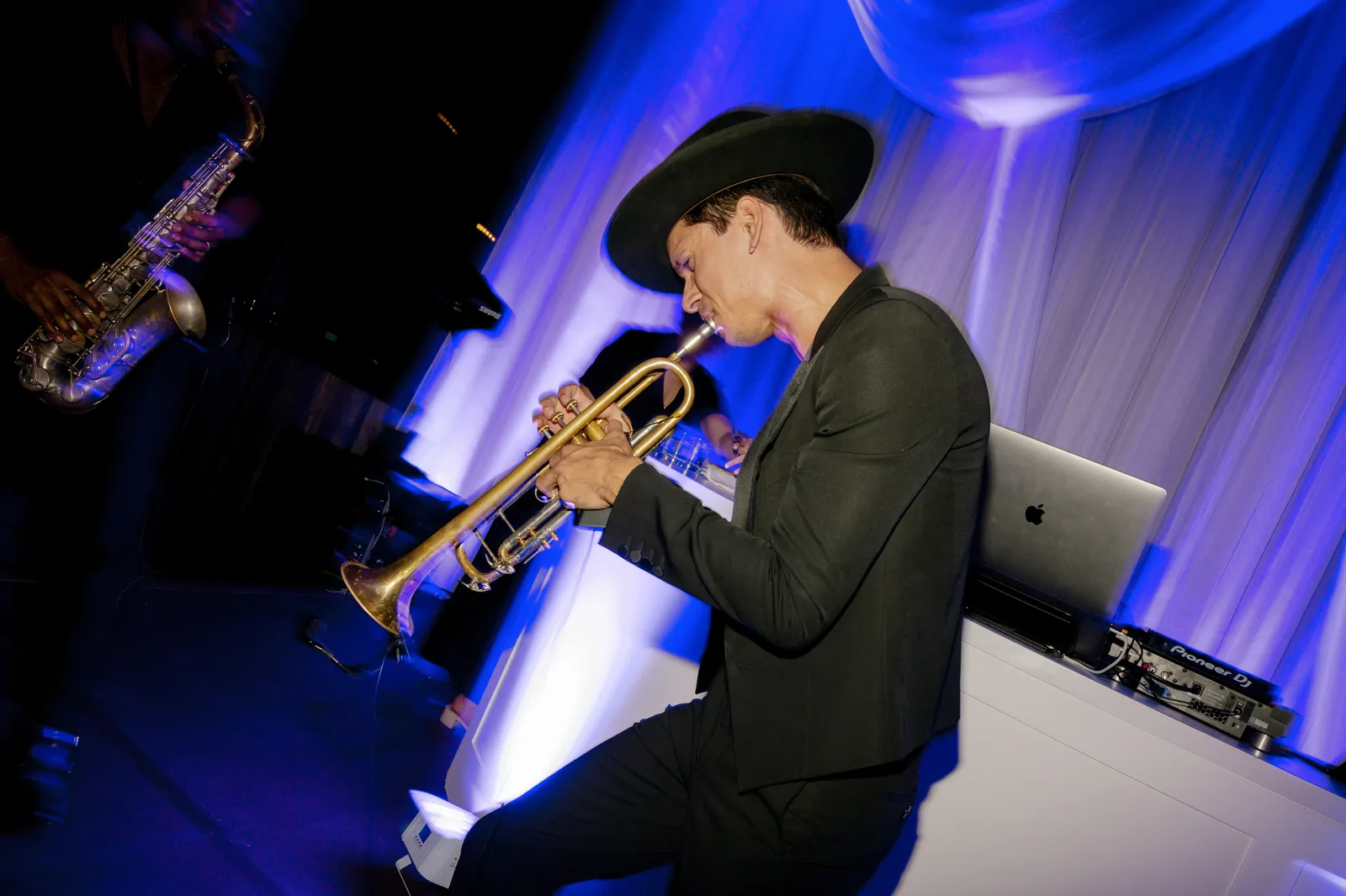 Trumpet player performing live beside the DJ booth in dramatic blue light